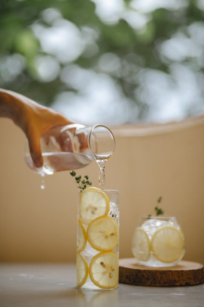 A clear glass of lemon and mint infused water being poured for a refreshing drink.