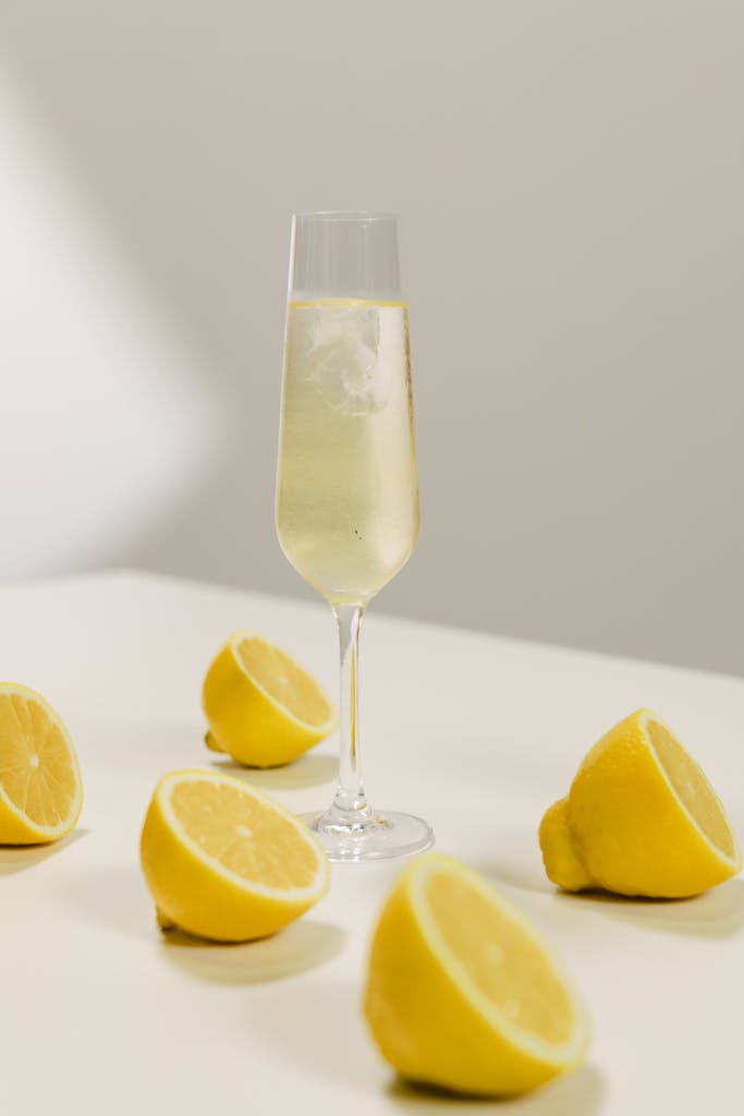 Champagne glass with fresh lemon slices on a white table, capturing a refreshing still life.