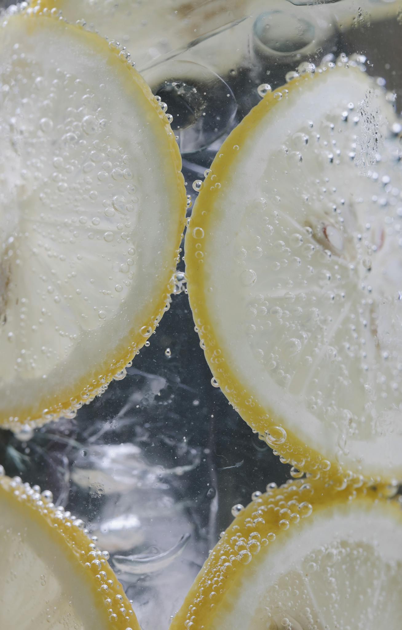 Close-up of lemon slices immersed in sparkling water with bubbles.