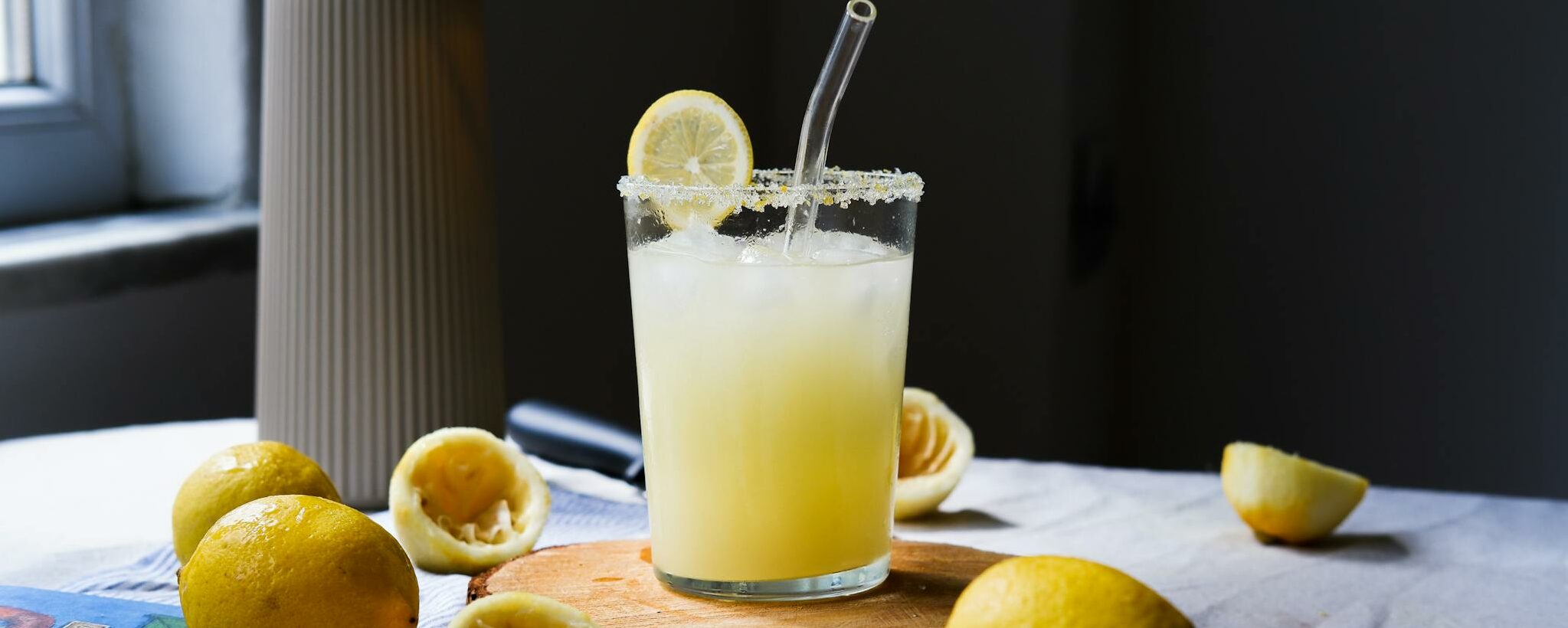Freshly made lemonade in a glass with lemons on a rustic table. Perfect refreshment.