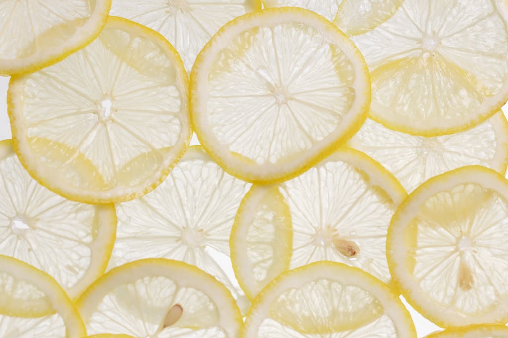 Vibrant close-up of fresh lemon slices arranged on a white surface, showcasing their texture and freshness.